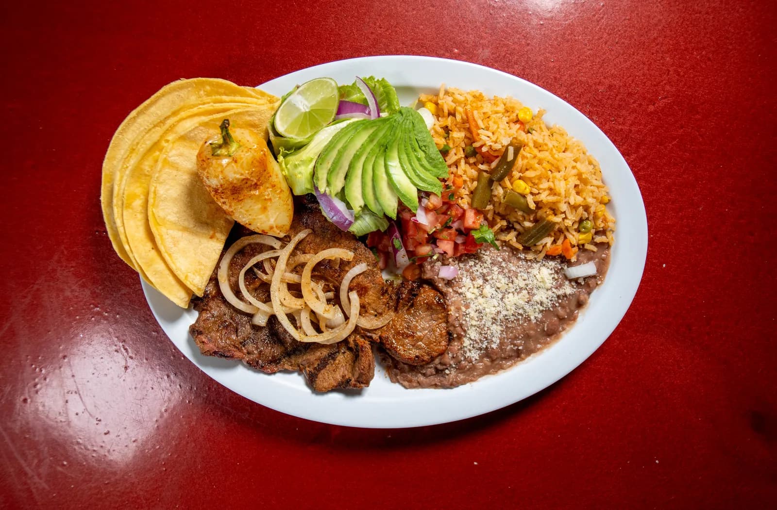 Plato de carne asada con arroz, frijoles, tortillas y aguacate