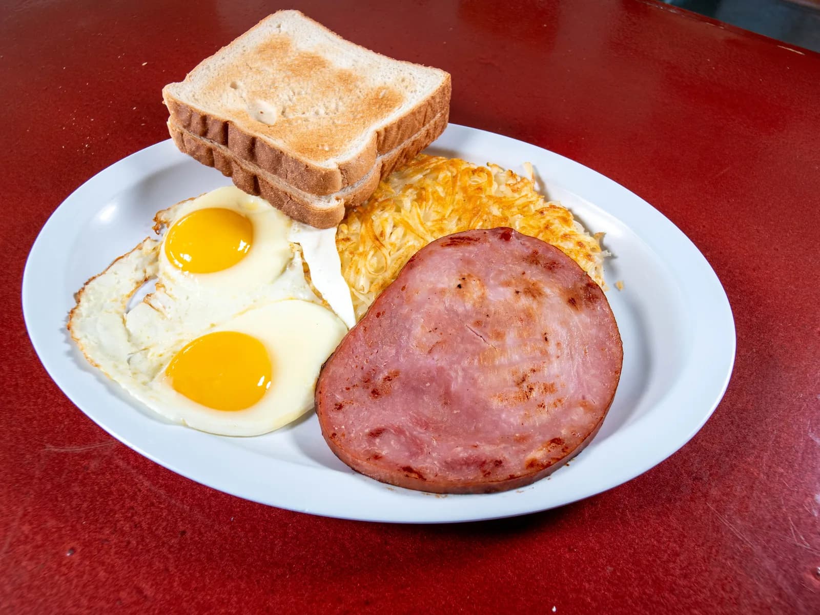 Desayuno de jamón con huevos, pan tostado y papas ralladas