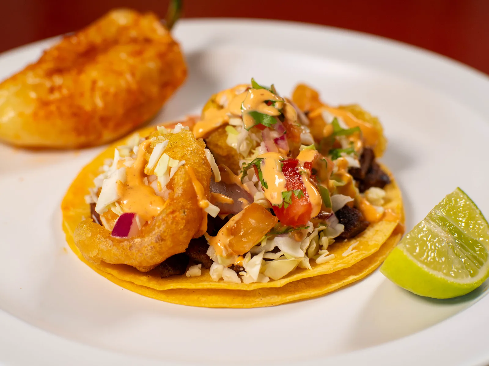 Taco de pescado con repollo, crema, salsa y limón